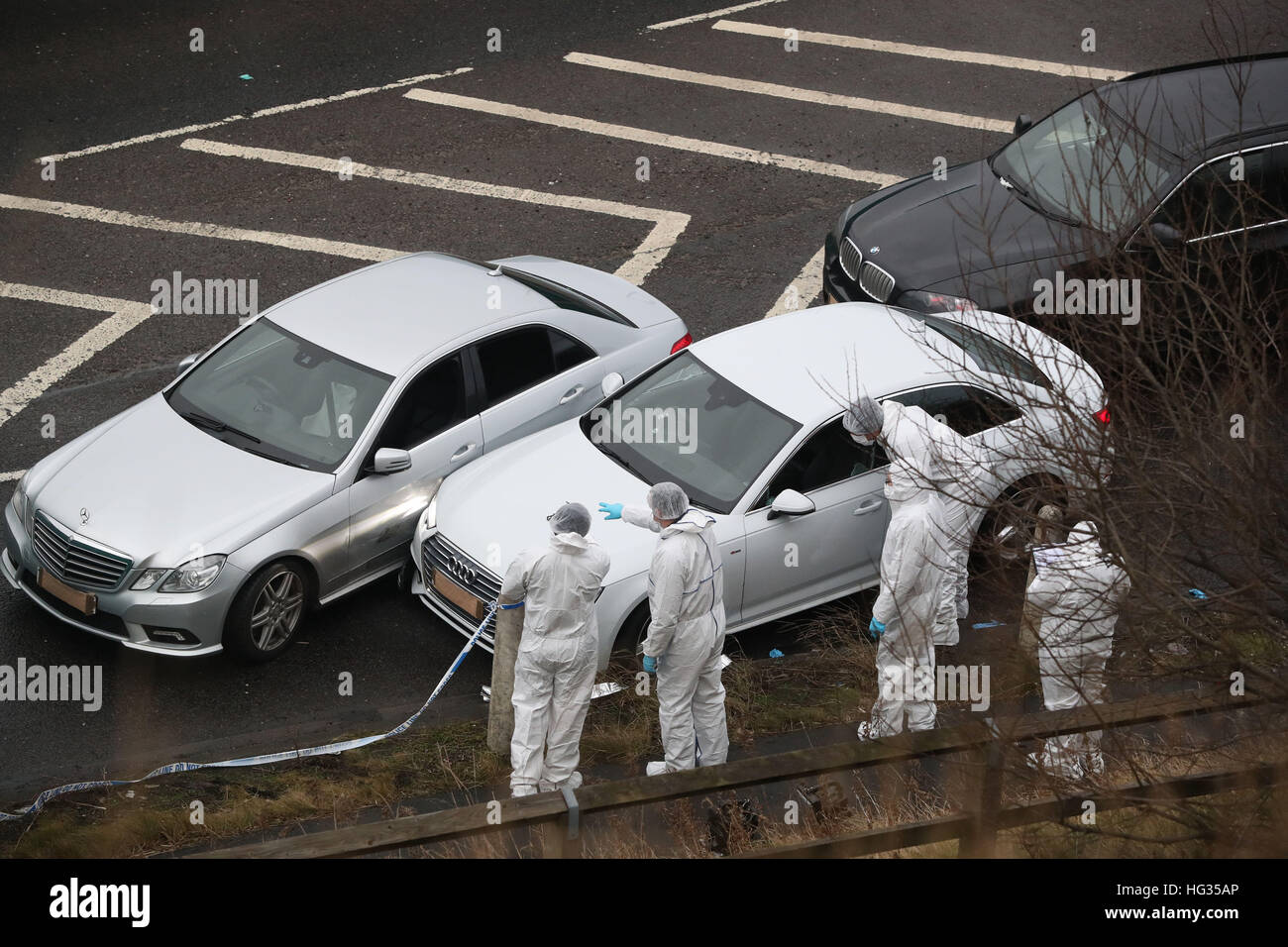 Police forensics officers examine a silver Audi with bullet holes in its windscreen at the scene near junction J24 of the M62 in Huddersfield where a man died in a police shooting during a 'pre-planned' operation at around 6pm on Monday. Stock Photo