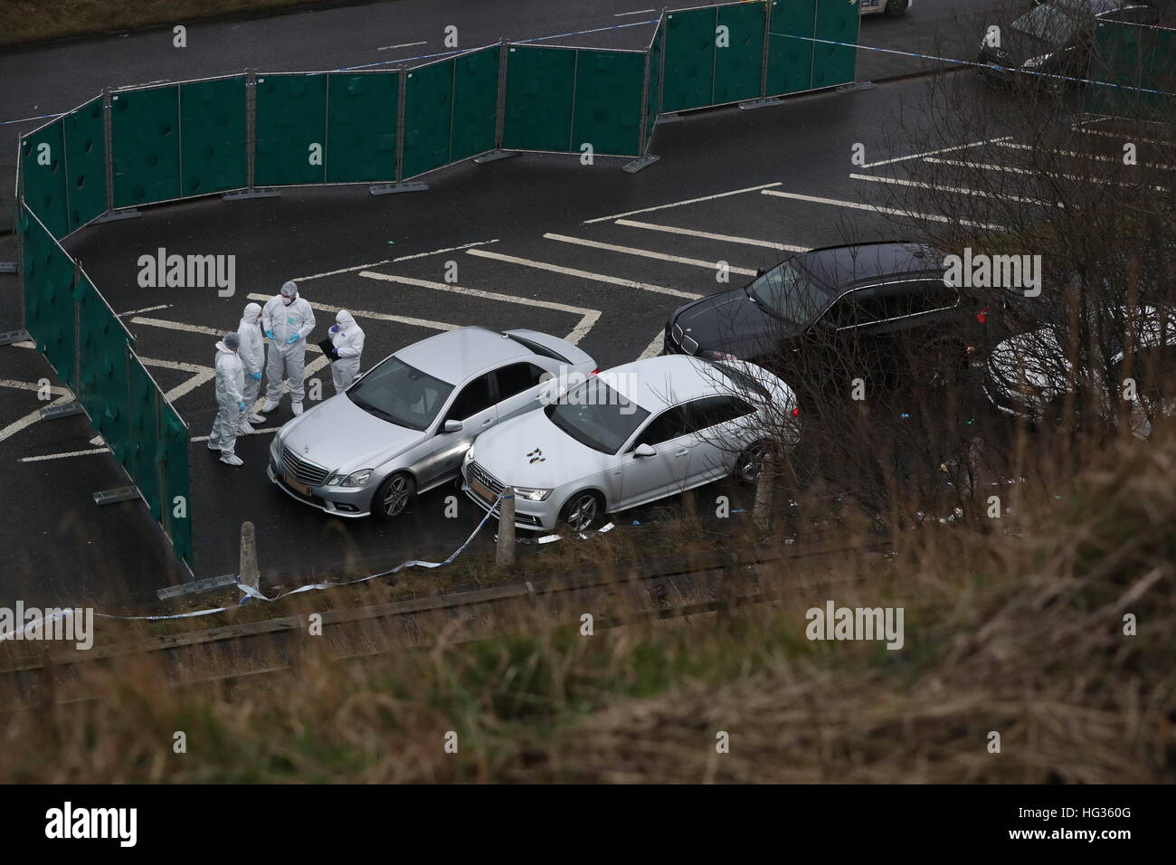 Police forensics officers near a silver Audi (centre) with bullet holes in its windscreen at the scene near junction J24 of the M62 in Huddersfield where a man died in a police shooting during a 'pre-planned' operation at around 6pm on Monday. Stock Photo