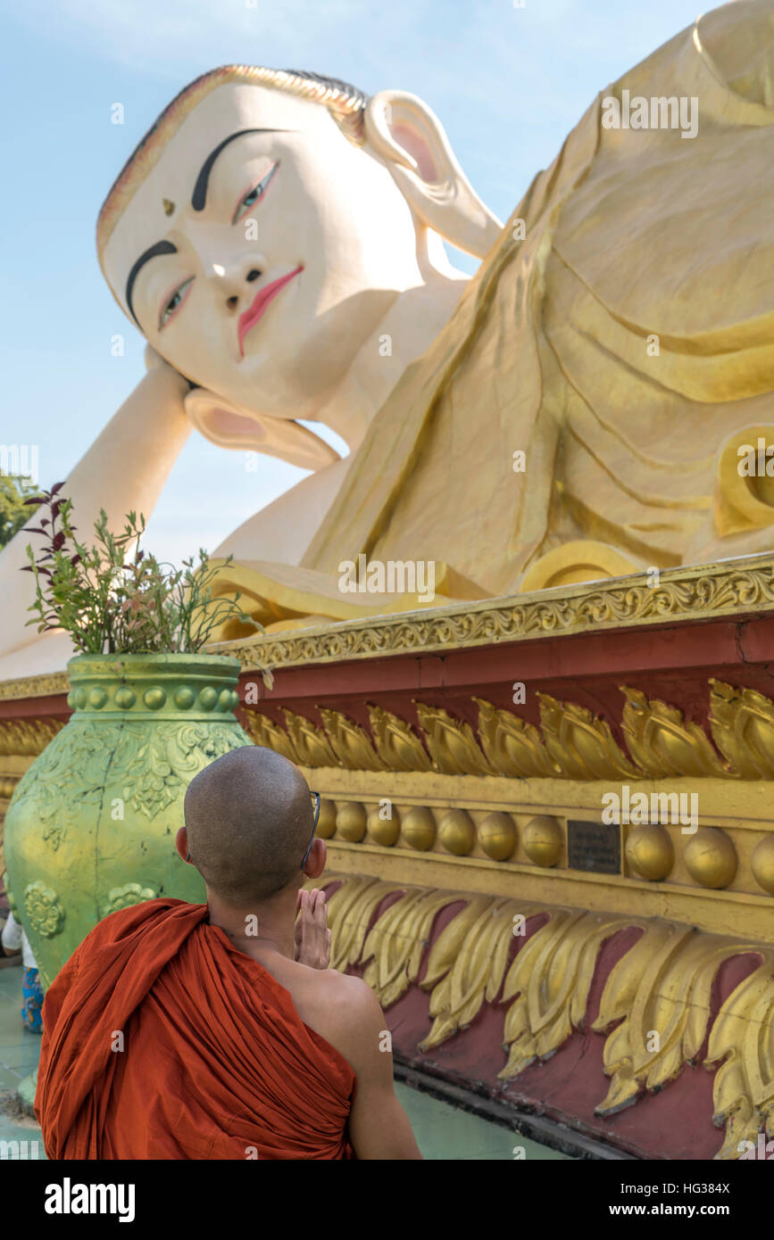 praying monk at the giant Myatharlyaung Reclining Buddha Image in Bago, Myanmar, Asia Stock Photo