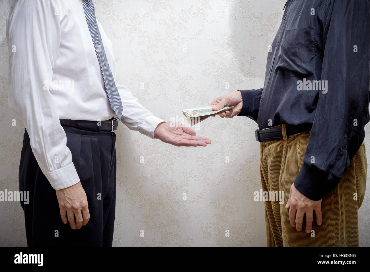 Corrupted man paying a Dollars banknotes bribe to a businessman, or politician, accepting corruption Stock Photo