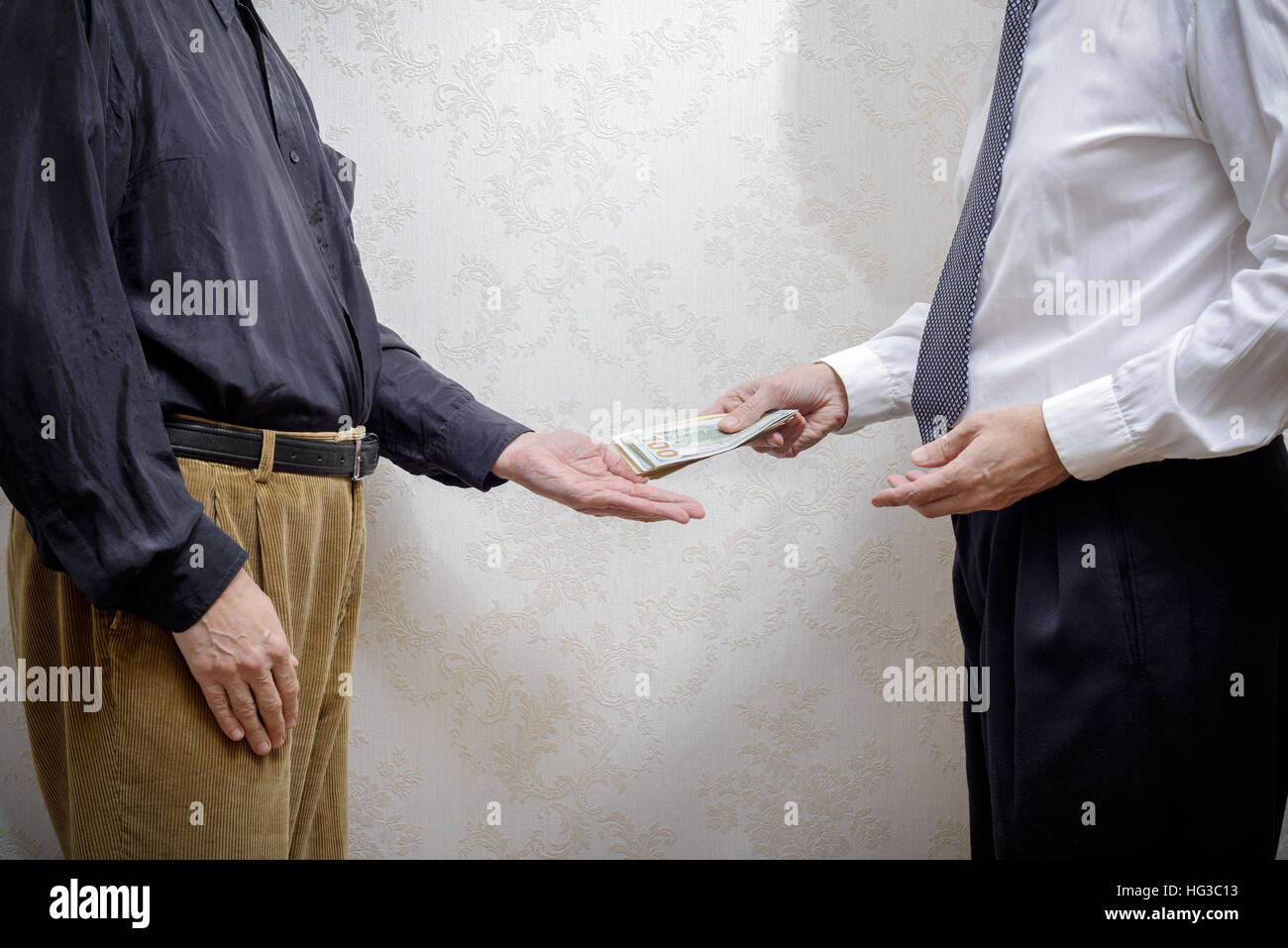 Corrupted businessman, or politician, paying a Dollars banknotes bribe to a man accepting corruption Stock Photo