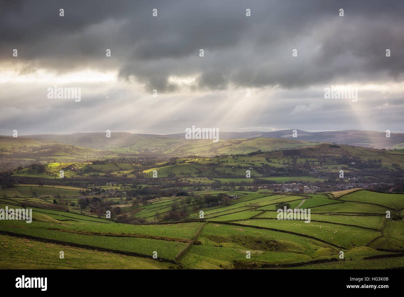 Rays of sunlight breaking through heavy clouds over rolling, green hills in the High Peak District, Derbyshire, England. Stock Photo