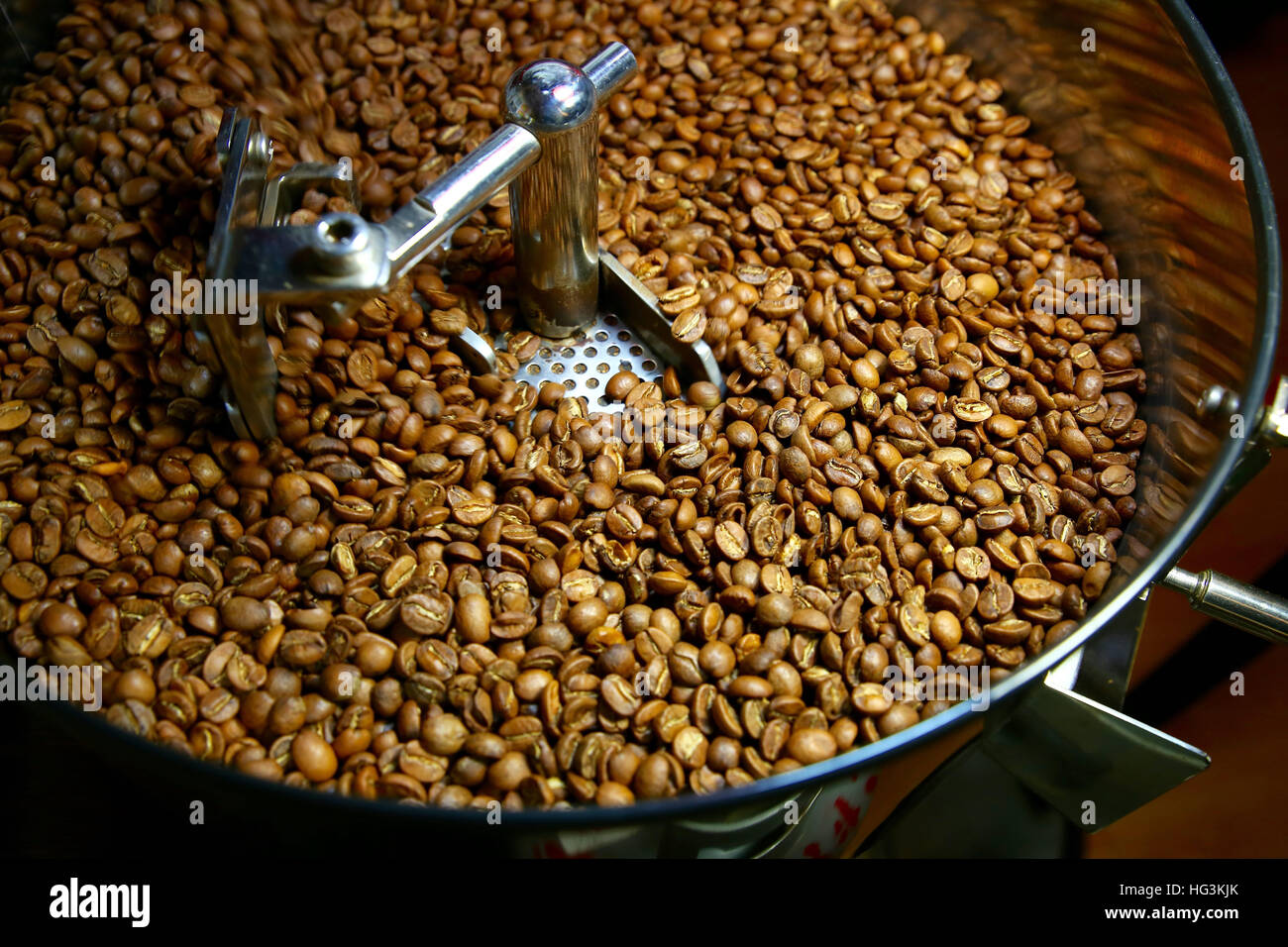 freshly roasted aromatic coffee beans over a modern machine used for roasting beans Stock Photo