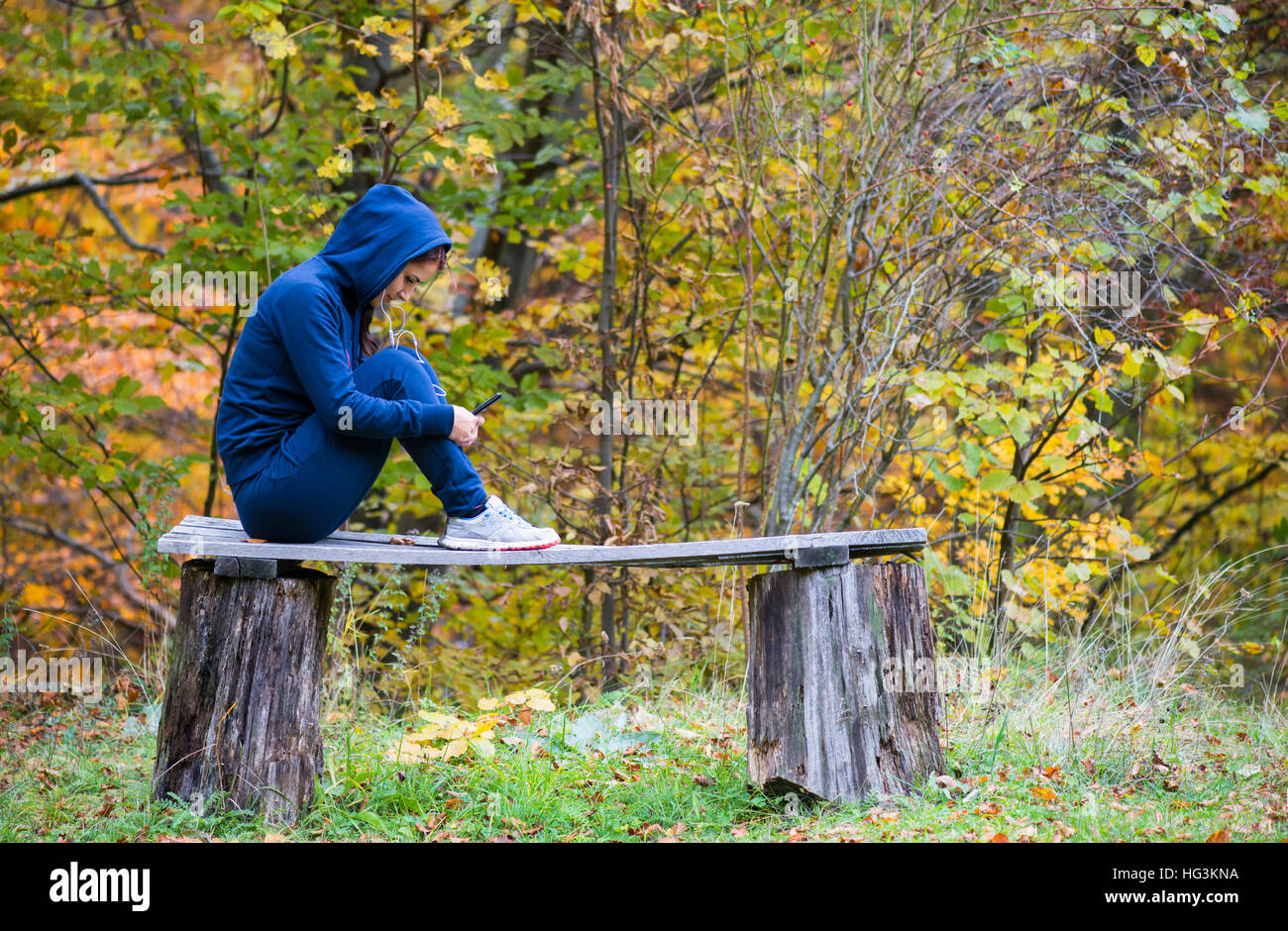 Young beautiful girl look and listening music on your mobile phone on the old  bench Stock Photo