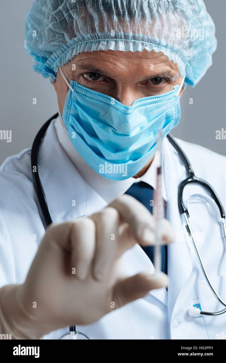 Serious doctor demonstrating hypodermic needle Stock Photo