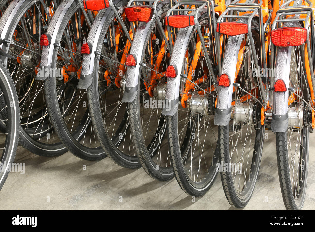 many of the rear wheels and mudguard of many orange bicycle in a parking Stock Photo