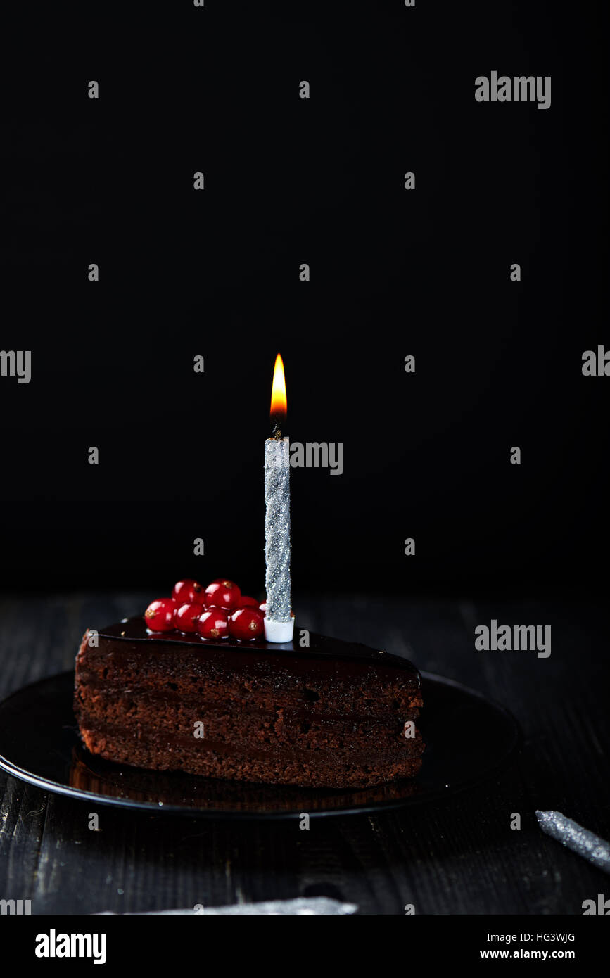 Slice of chocolate cake with a single lit candle Stock Photo - Alamy