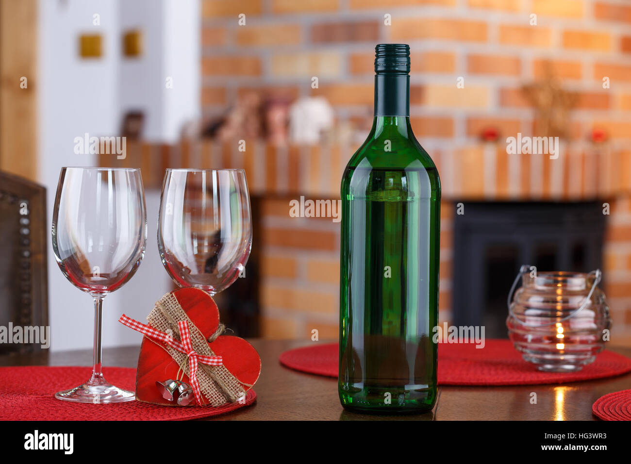 Still life with wine bottles, glasses and heart symbol, on the background a brick fireplace Stock Photo