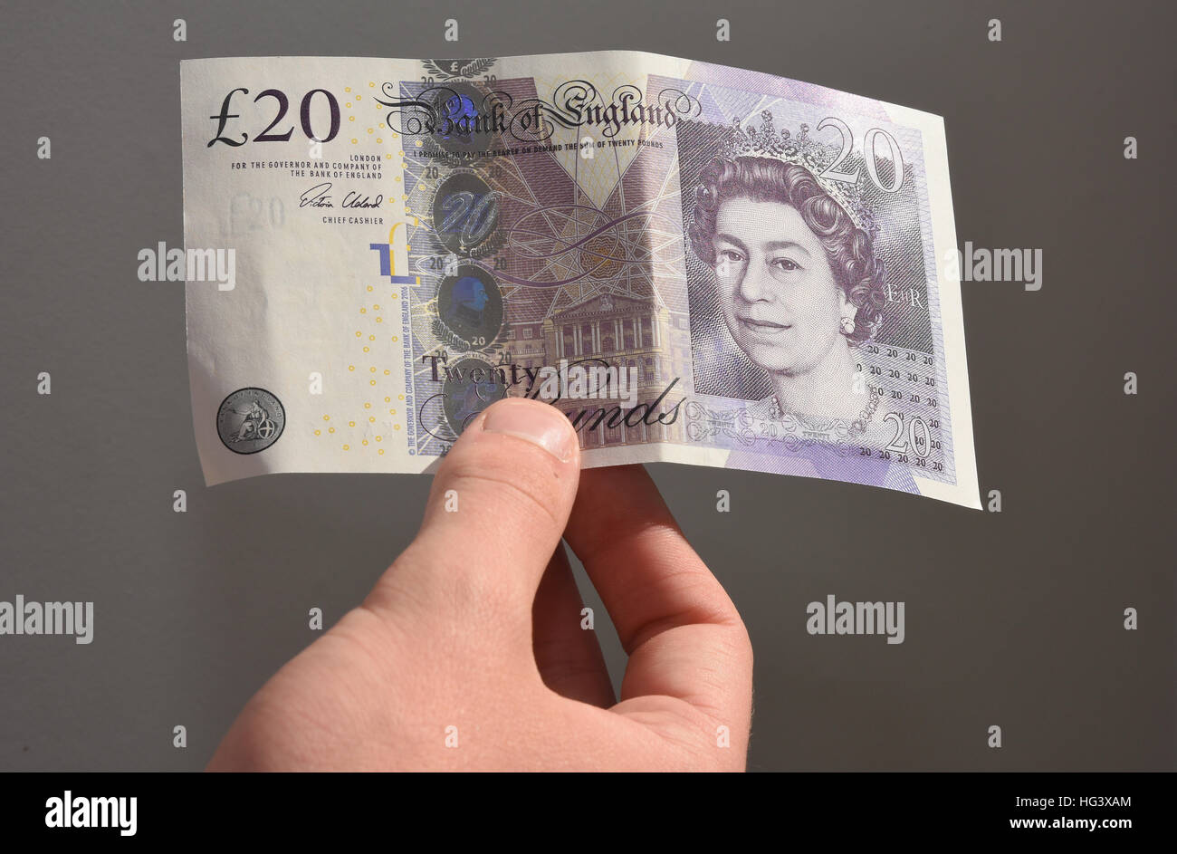 Close up of teenage boy holding up a UK twenty pound note Stock Photo