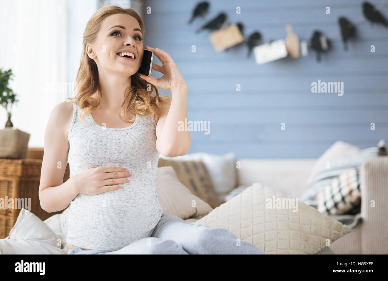 Amused pregnant woman talking on cellphone in bed Stock Photo