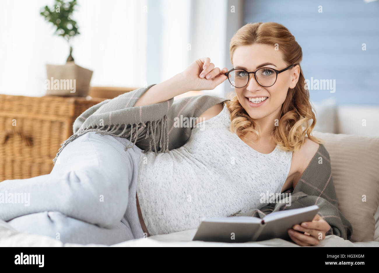 Pregnant woman reading book in bed Stock Photo