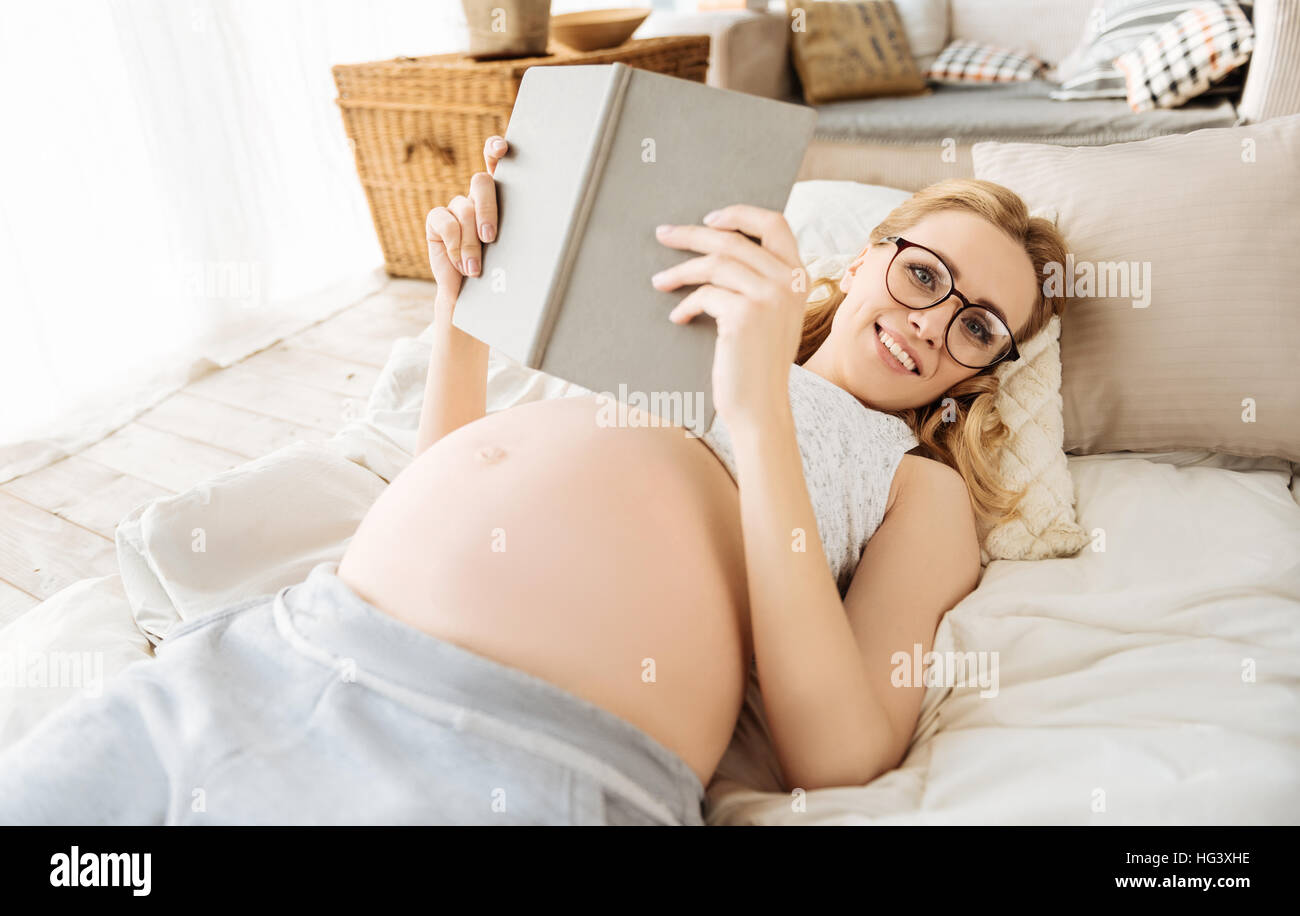 Pregnant woman holding a book in bedroom Stock Photo