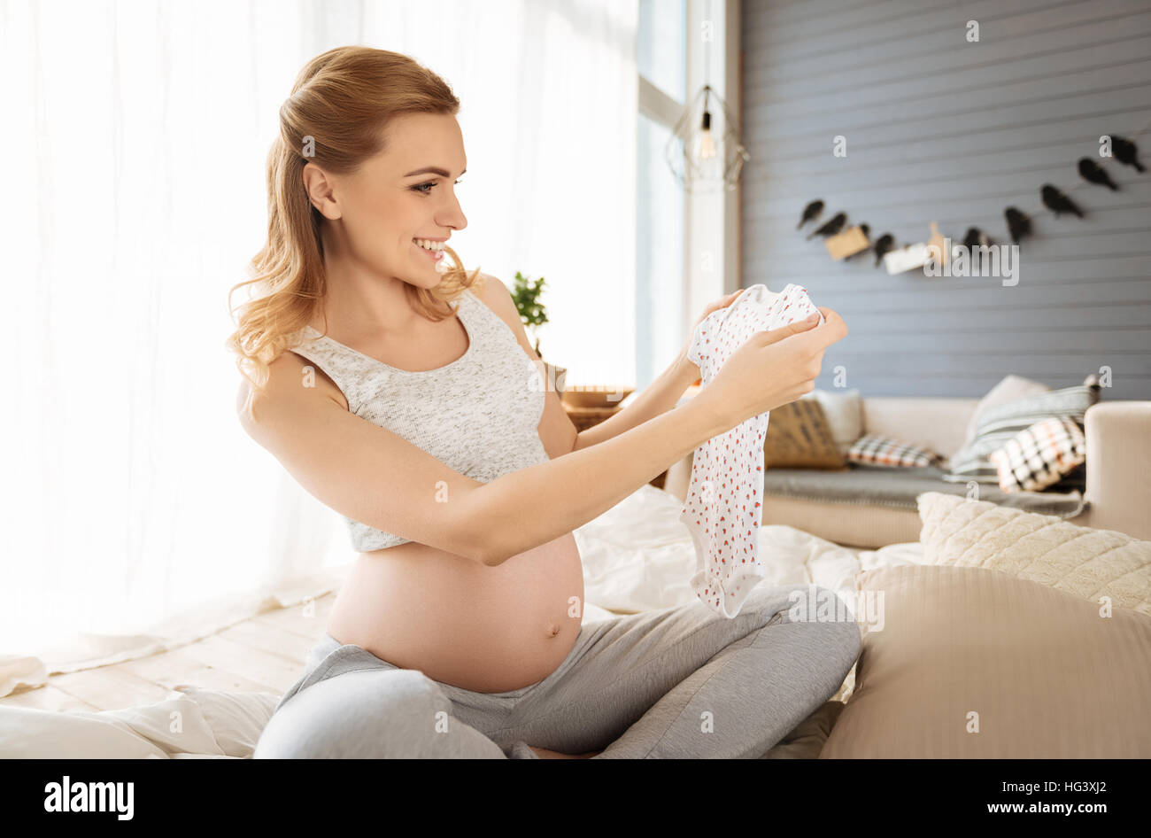 Pregnant woman holding baby clothes Stock Photo