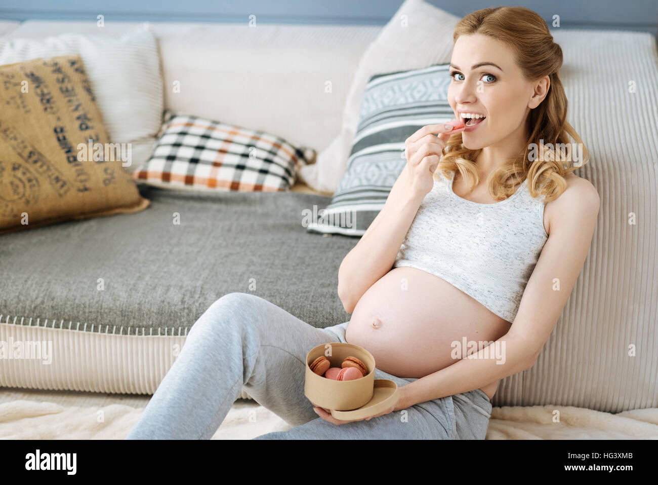 Pregnant joyful woman eating macaroons Stock Photo