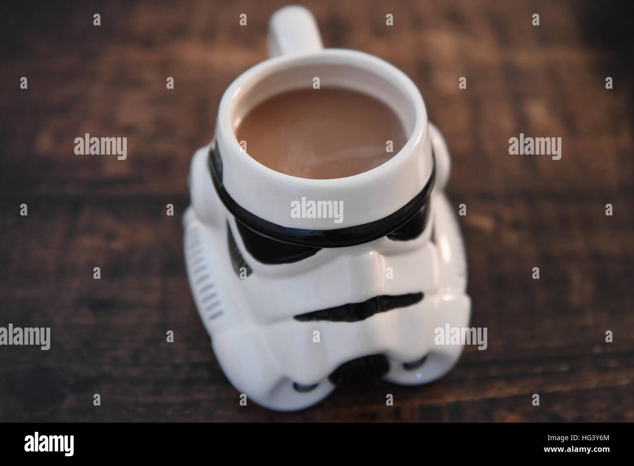 A Storm Trooper helmet mug filled with tea on a dark wood table, star wars merchandise. Stock Photo