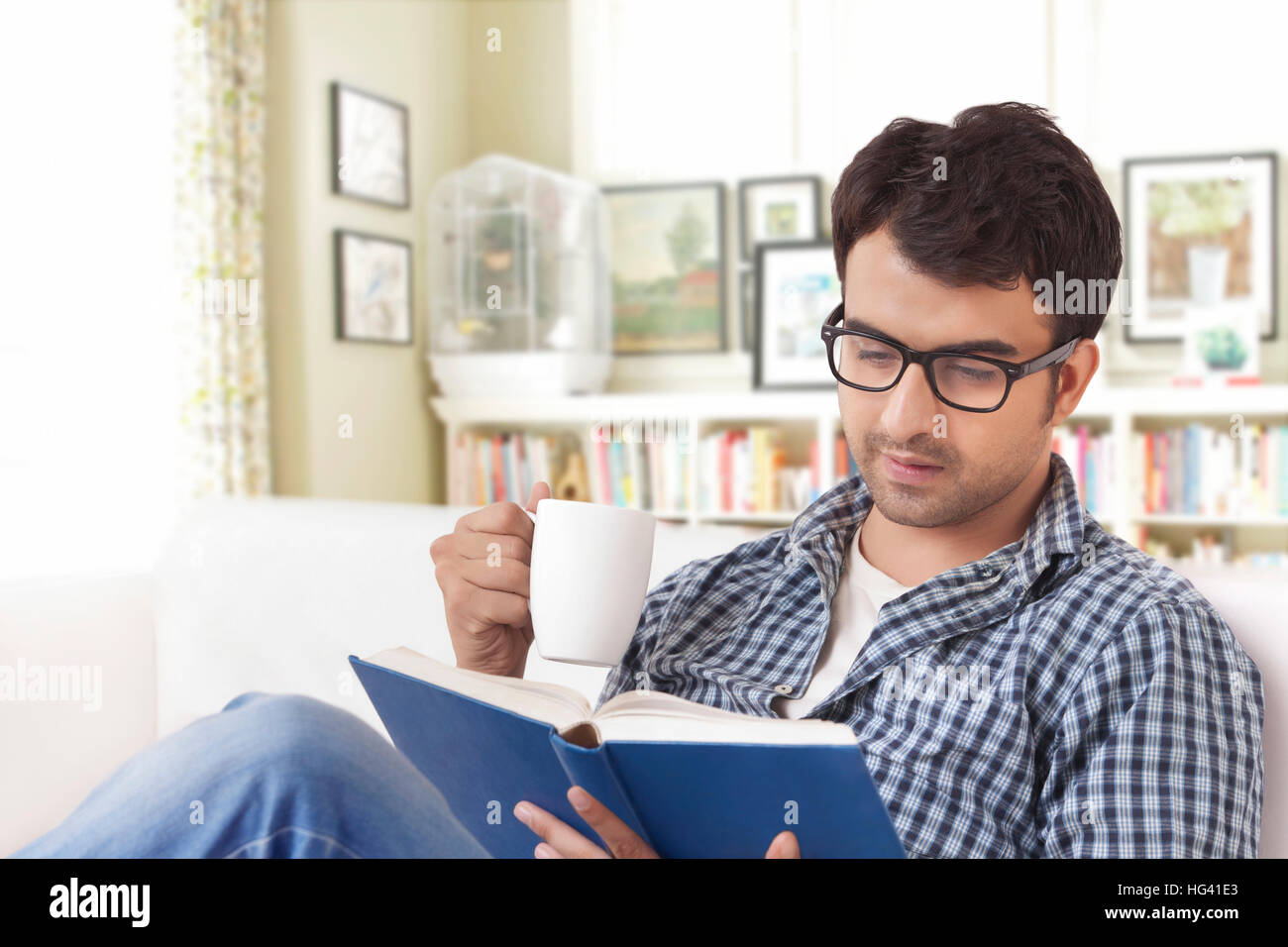 Young man reading book and drinking coffee Stock Photo