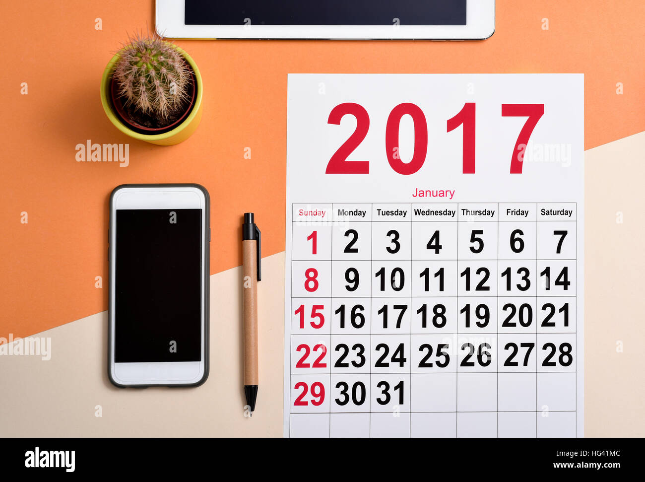 high-angle shot of a 2017 calendar on an office desk next to a pen, a smartphone, a cactus and a tablet Stock Photo