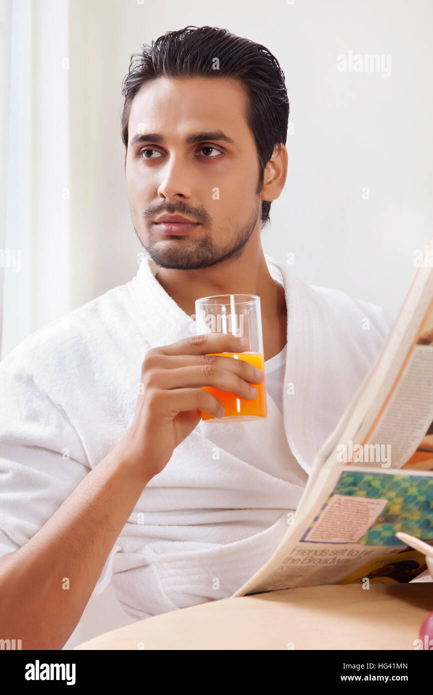 Portrait of man drinking juice holding newspaper Stock Photo