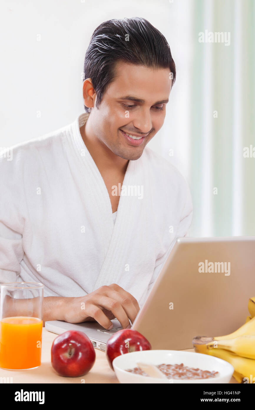 Man using laptop at breakfast table Stock Photo