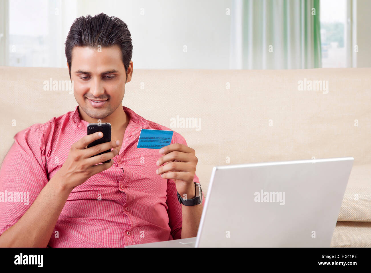 Young man with laptop and mobile phone shopping online Stock Photo