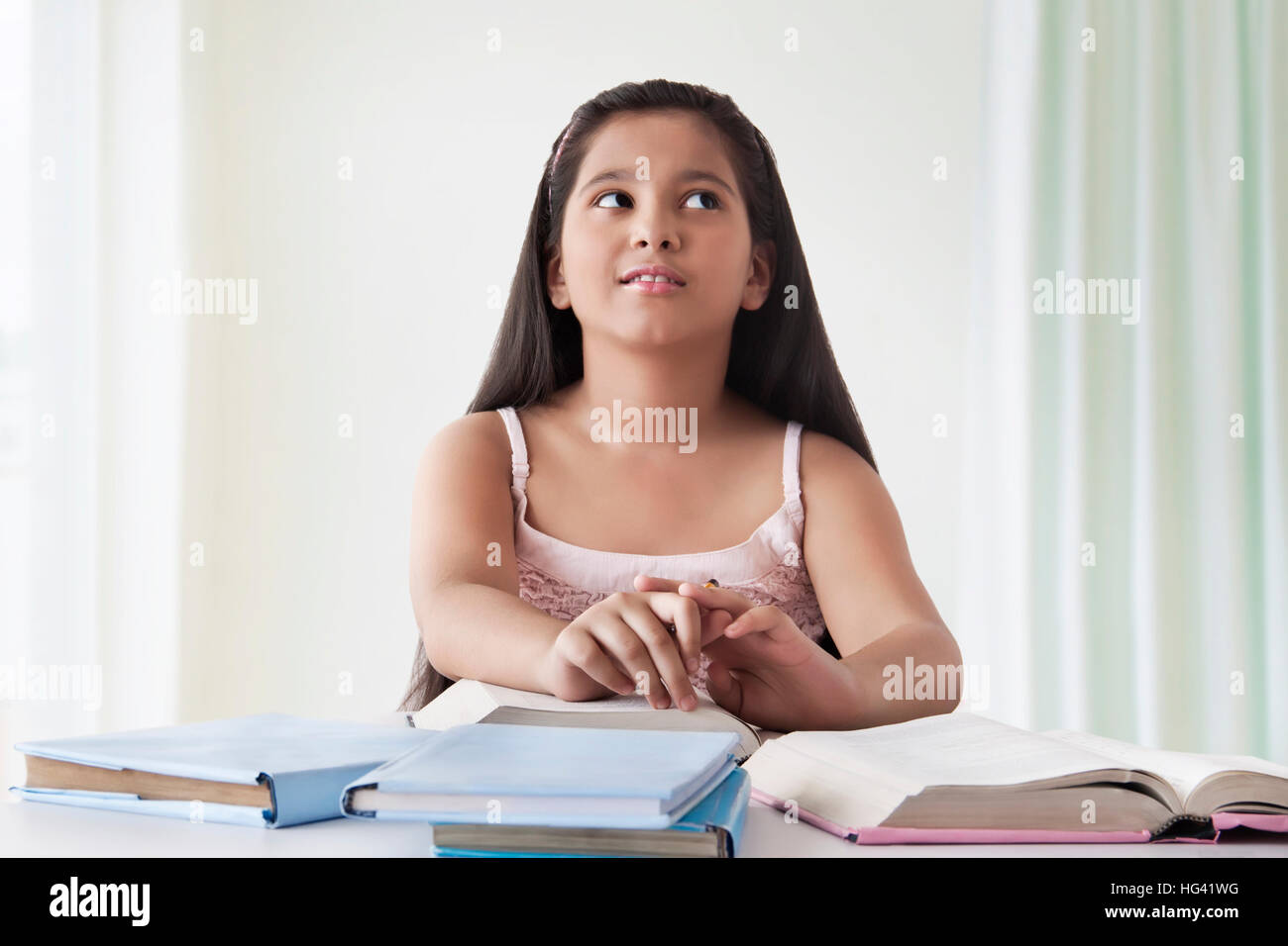Portrait of cute girl thinking at desk with books Stock Photo - Alamy