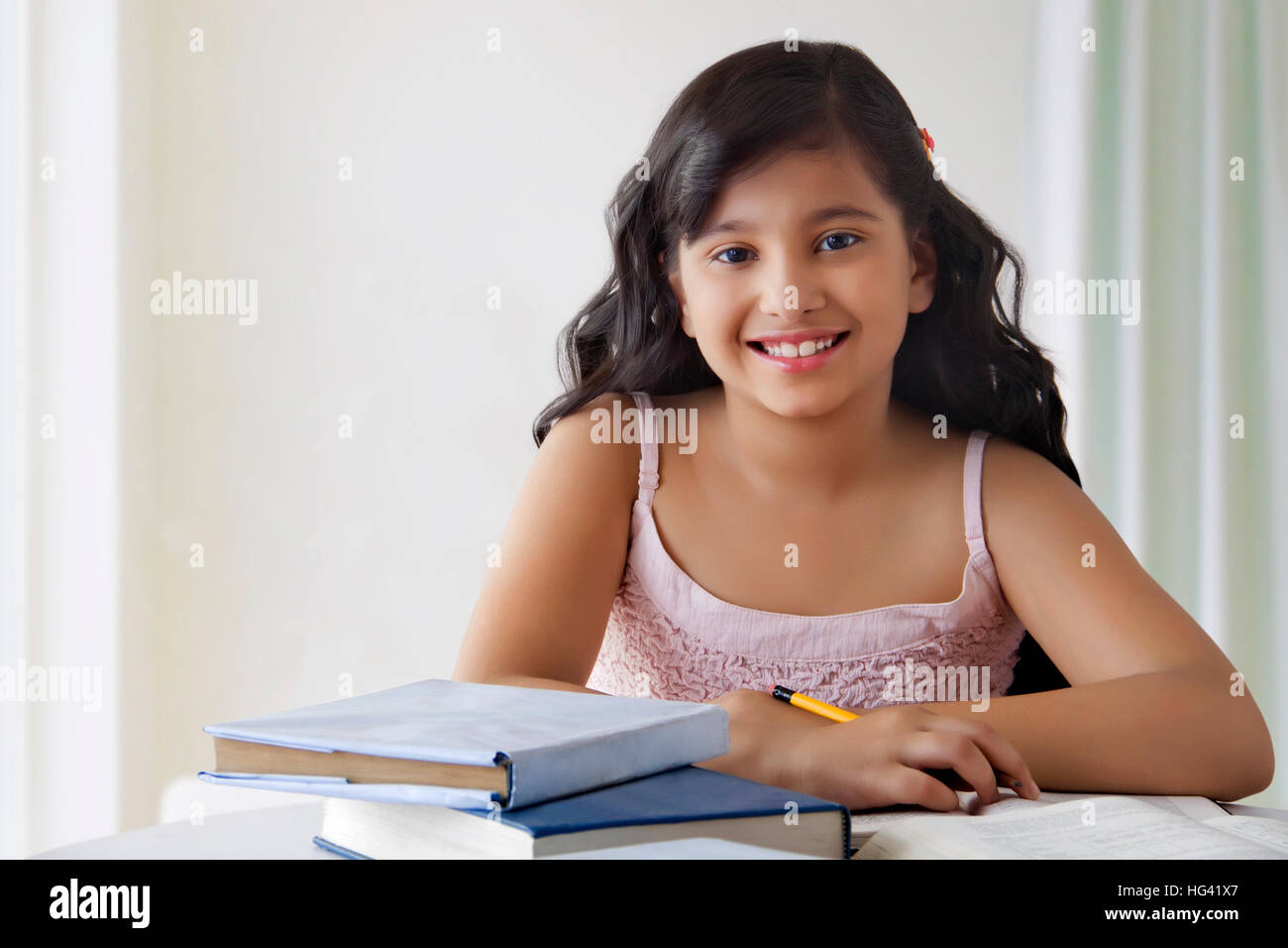 Portrait of smiling cute girl at desk with books Stock Photo