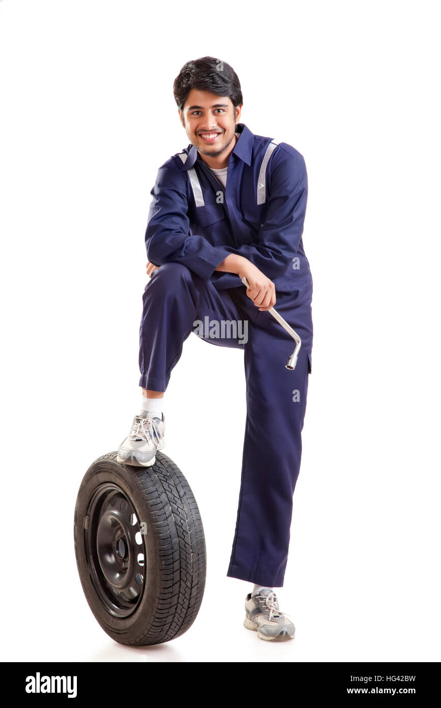 Portrait of car mechanic with spare tyre Stock Photo