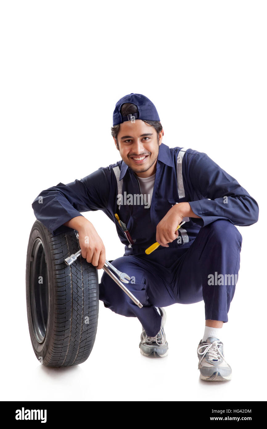 Portrait of car mechanic with spare tyre and hand tools Stock Photo
