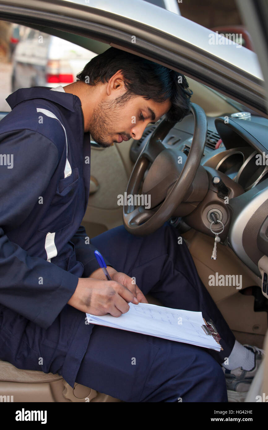 Mechanic examining car and writing on clipboard Stock Photo - Alamy