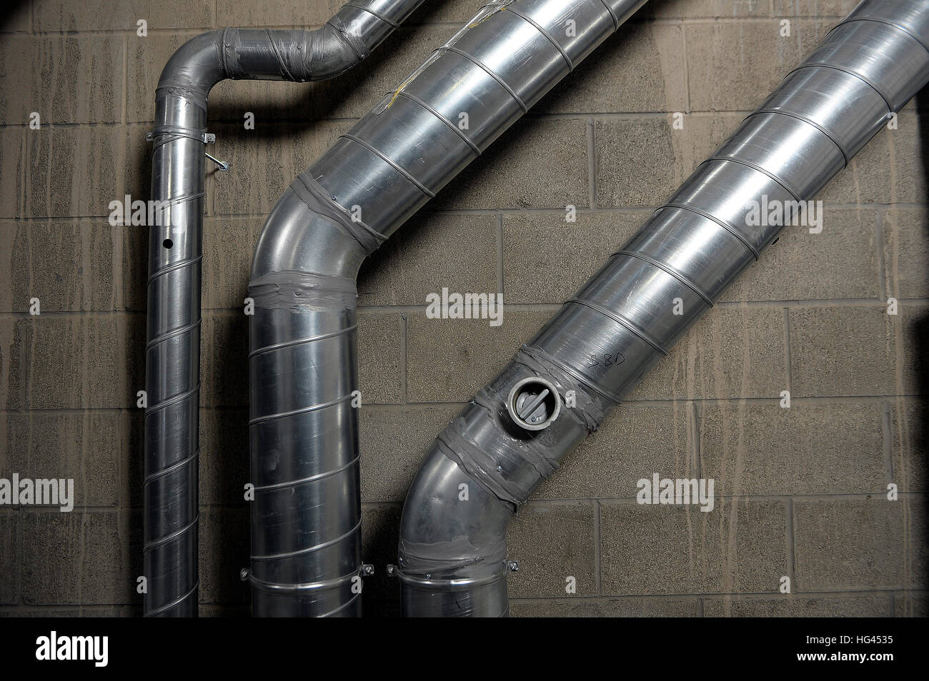 Industrial aluminium air conditioning pipes mounted on a breeze block