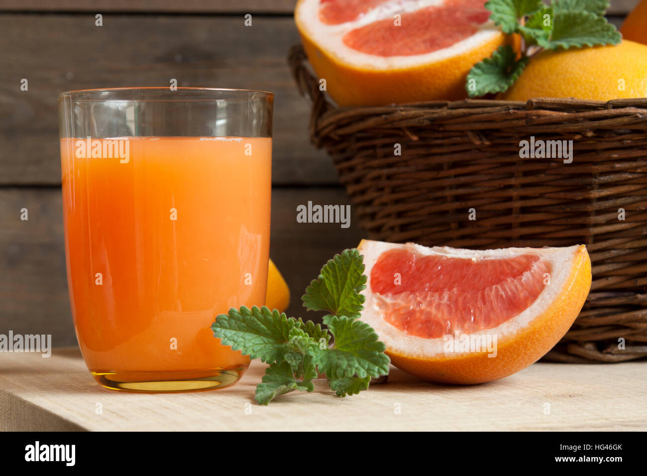 Natural and fresh grapefruit juice in glass with freshly harvested grapefruit in basket on dark wooden background Stock Photo