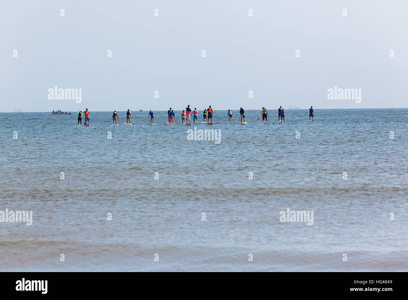 Ocean beach stand up paddlers men women on boards paddling outing on seas water Stock Photo
