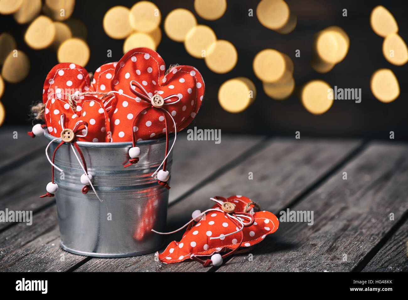 Red hearts in zinc bucket on wooden background in vintage and retro