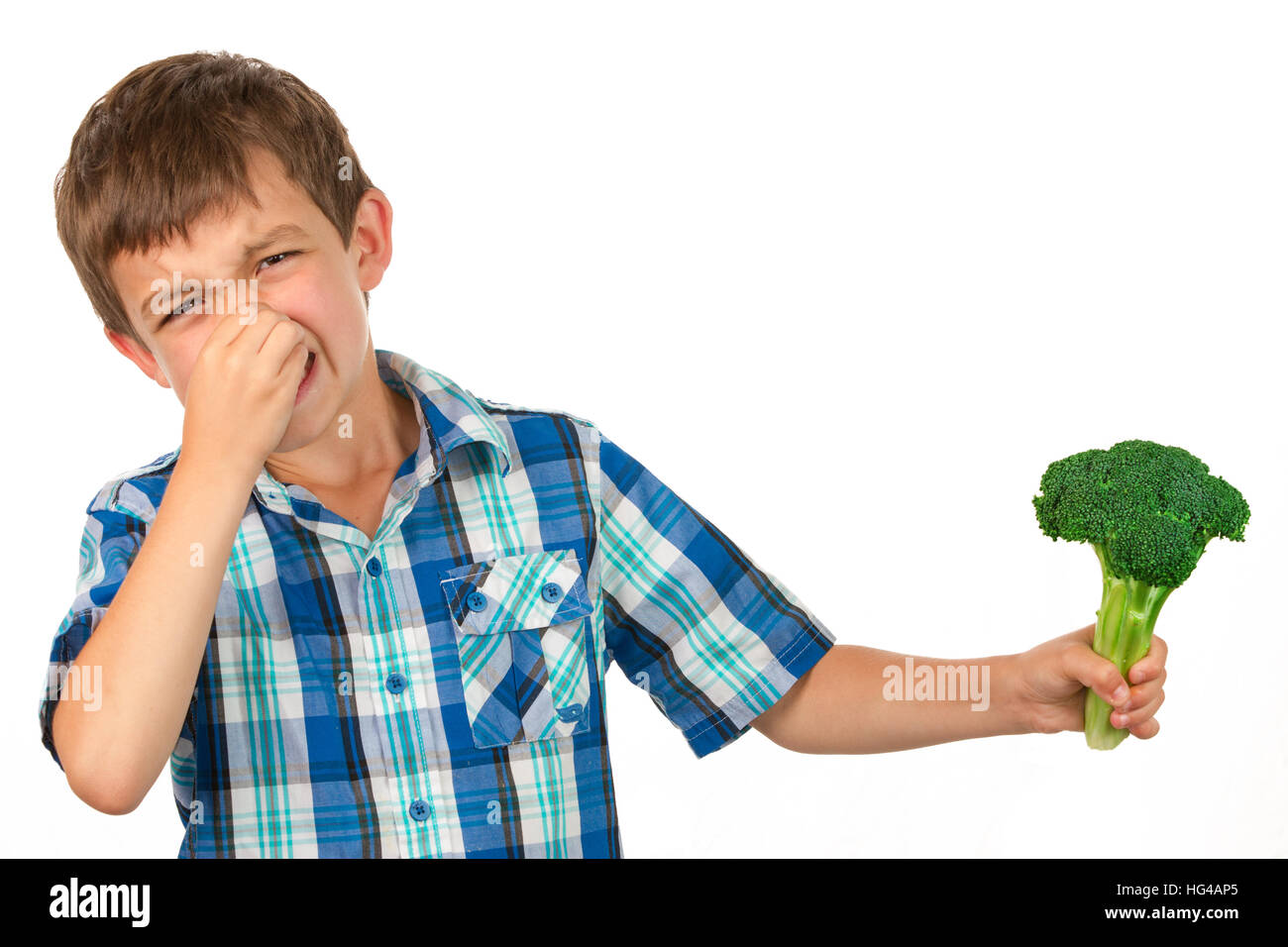 Small Boy Holding a Bunch of Broccoli and has a disgusted look on his face Stock Photo