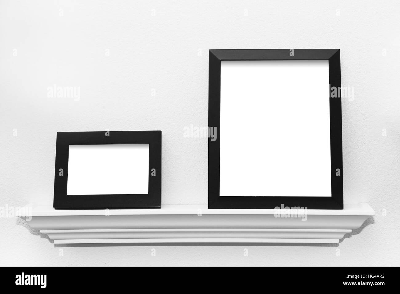 Two blank black picture frames on a picture display ledge attached to a