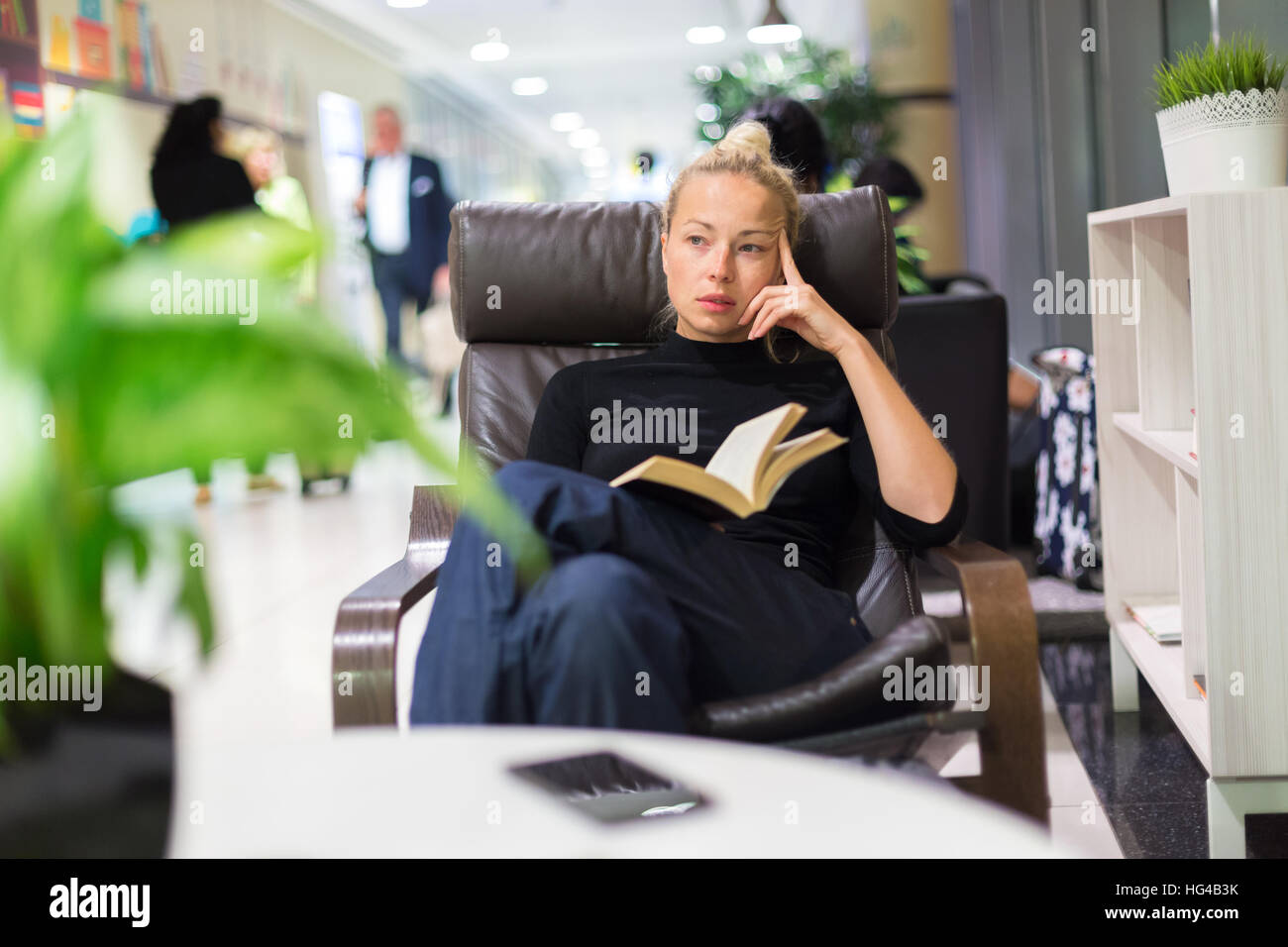 Charming girl sitting by wooden table and reading book Stock Photo - Alamy