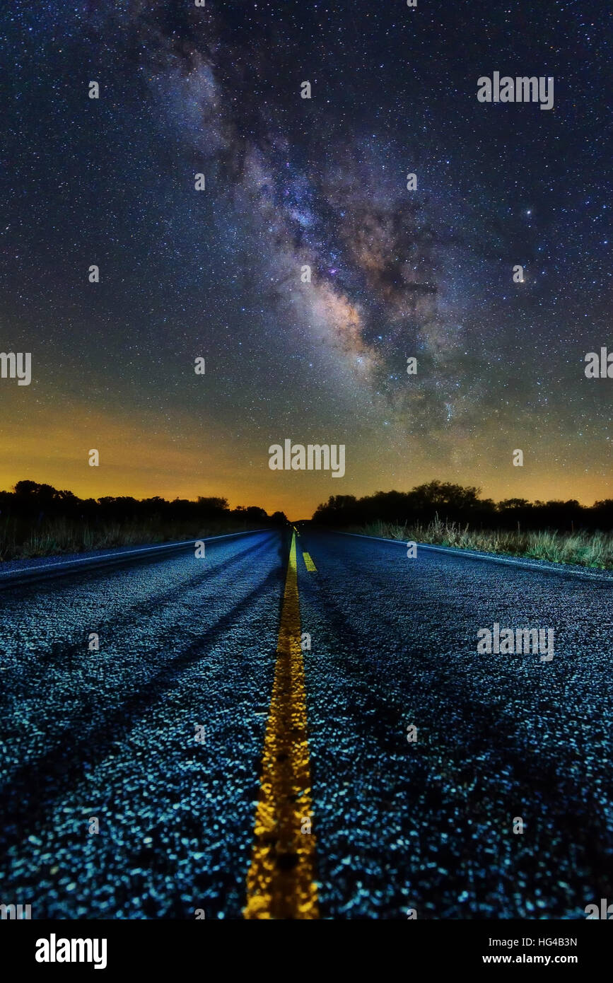 Milky way appear on the middle of the road with double solid yellow line point to the milky way core. Scenic road at night time driving to heaven them Stock Photo