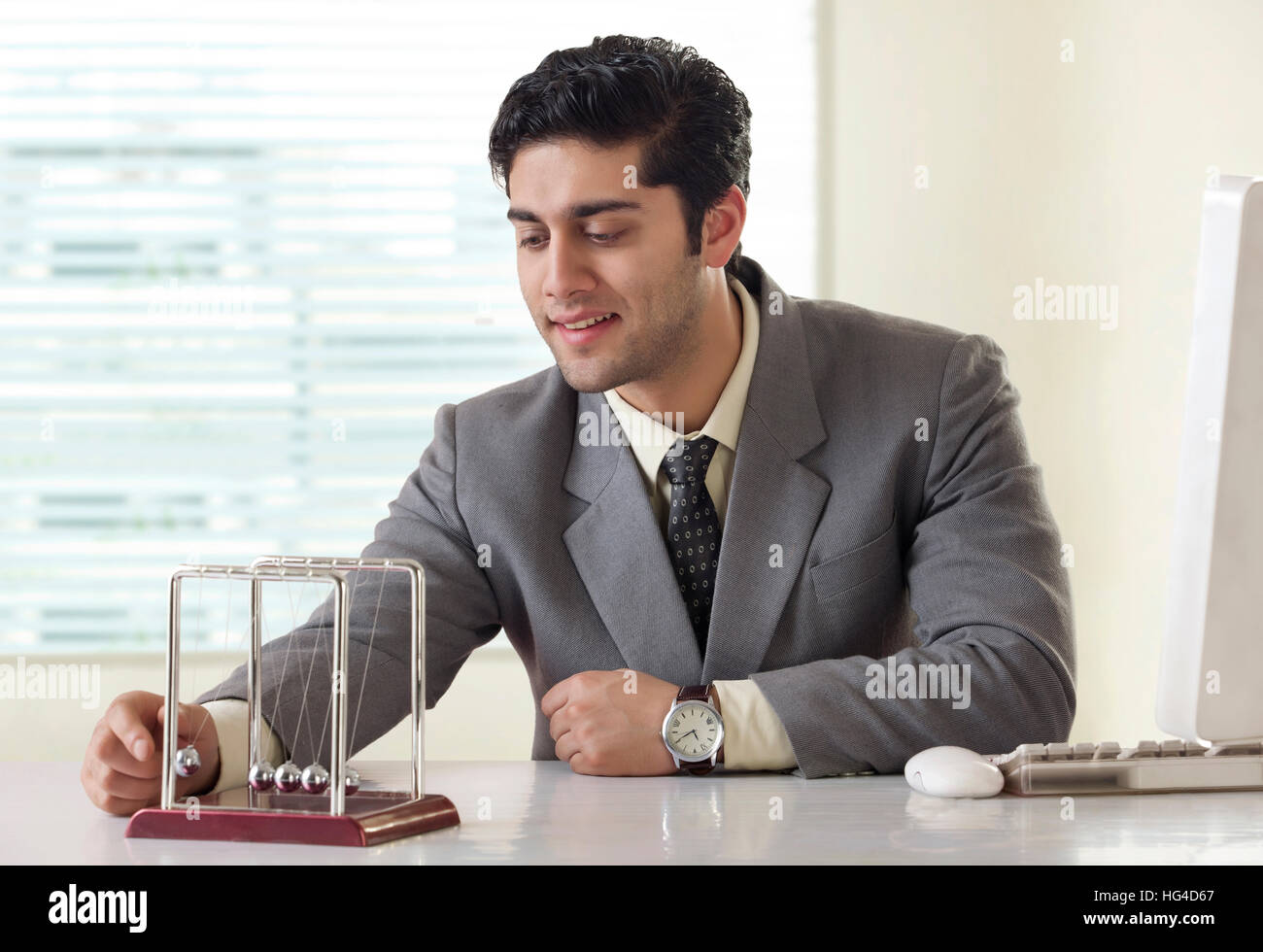 Businessman looking at a pendulum on office desk Stock Photo Alamy