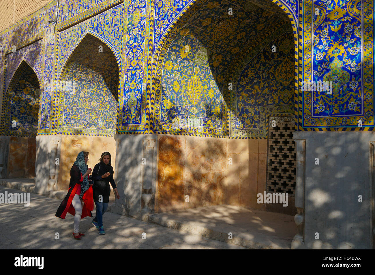 Two Iranian girls walking past courtyard walls, Imam Mosque, UNESCO, Isfahan, Iran, Middle East Stock Photo