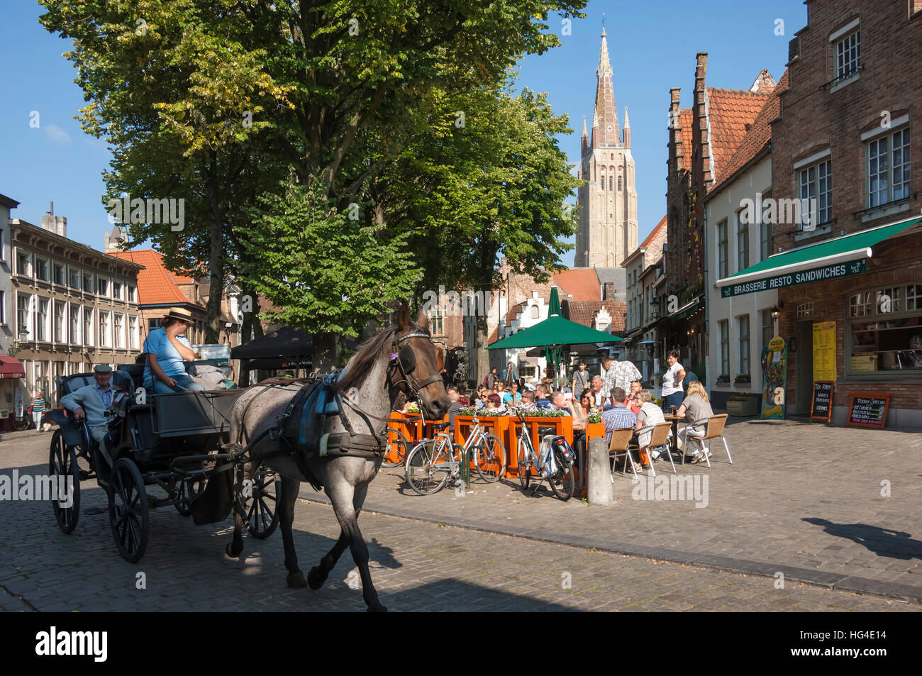 Square with cafe, horse and carriage, and spire of Church of Our Lady, Bruges, Belgium Stock Photo