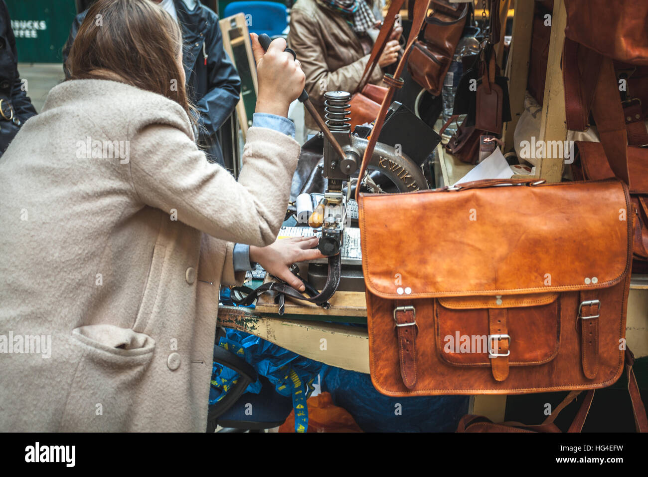 Woman manufacturing purses and leather handbags directly on the street hot print with a kwik-print stamp machine Stock Photo