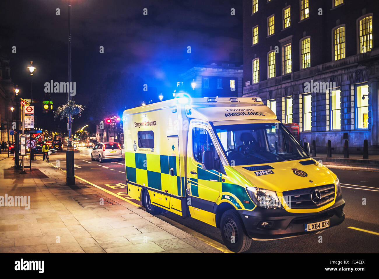 NHS, London yellow ambulance on duty with blue light on at night Stock