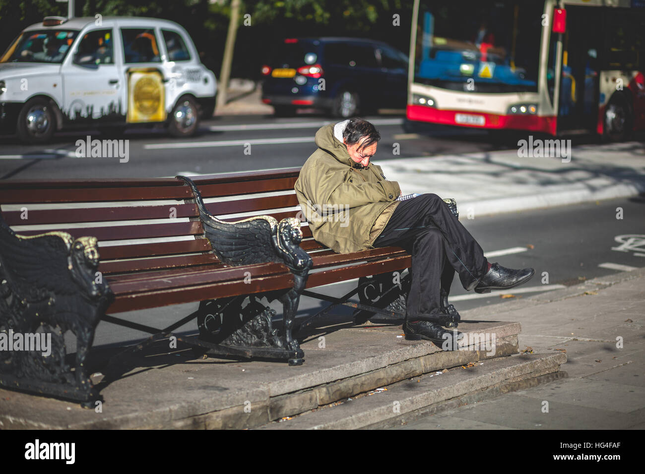 Middle-age man taking a nap on a bench in London Stock Photo