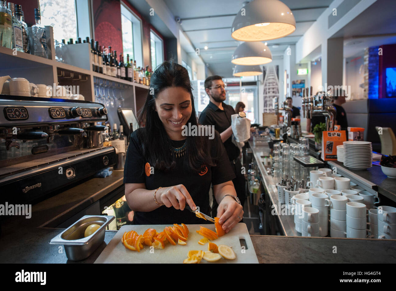 A girl slicing oranges for cocktails at the bar at Brigade Stock Photo