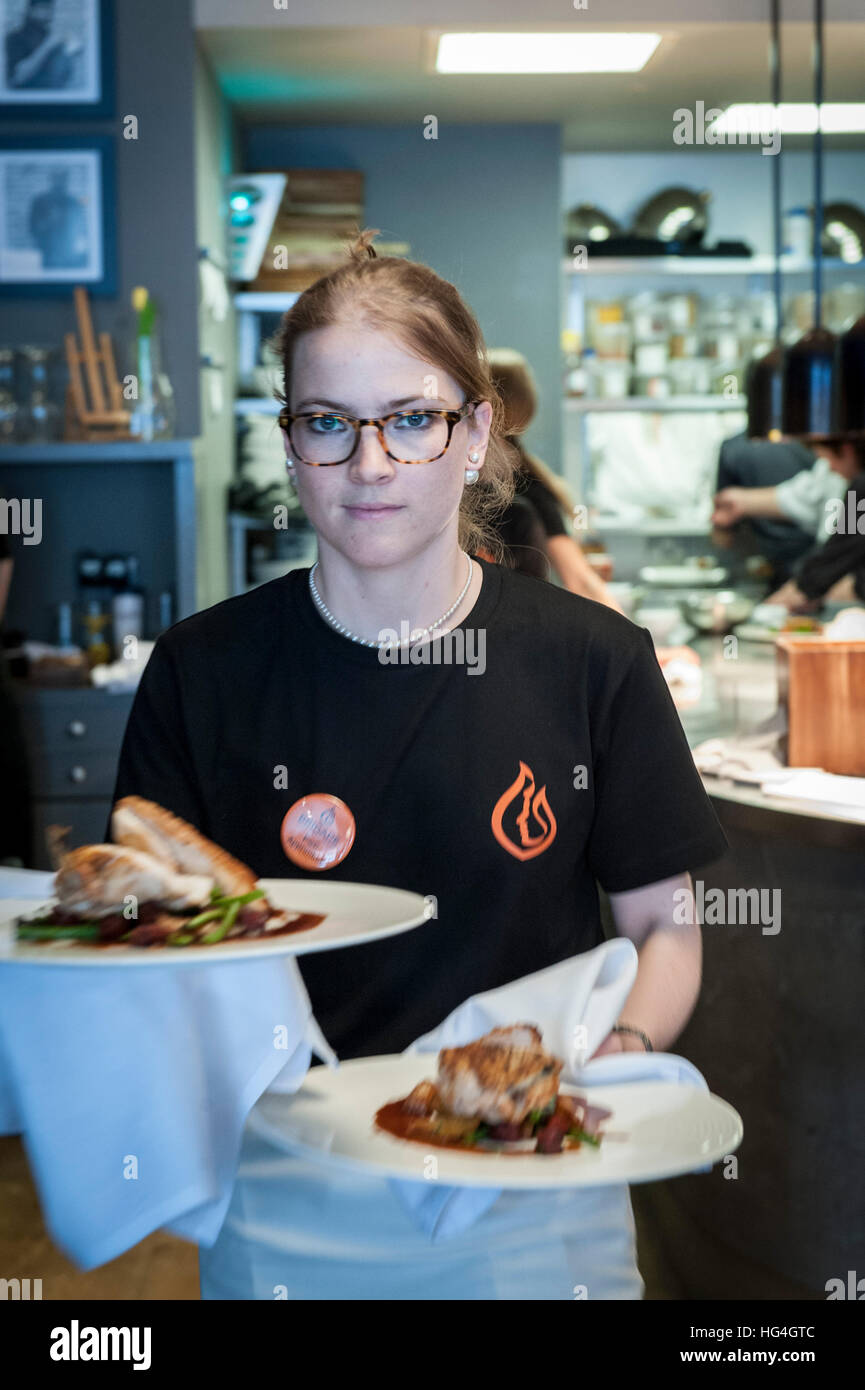 A waitress carries two plates of food to the tables Stock Photo