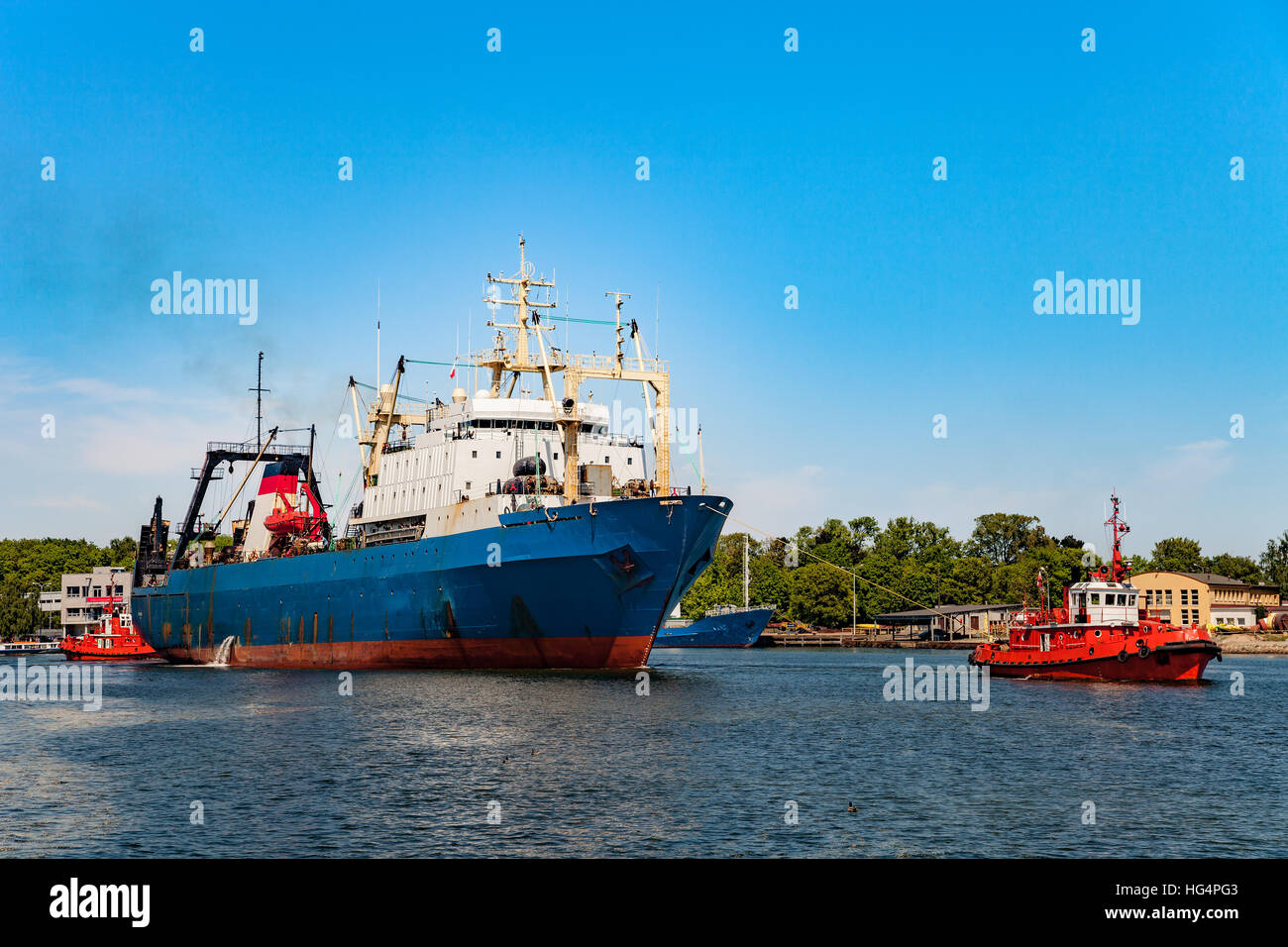 Tugboat towing fishing ship in port of Gdansk, Poland. Stock Photo