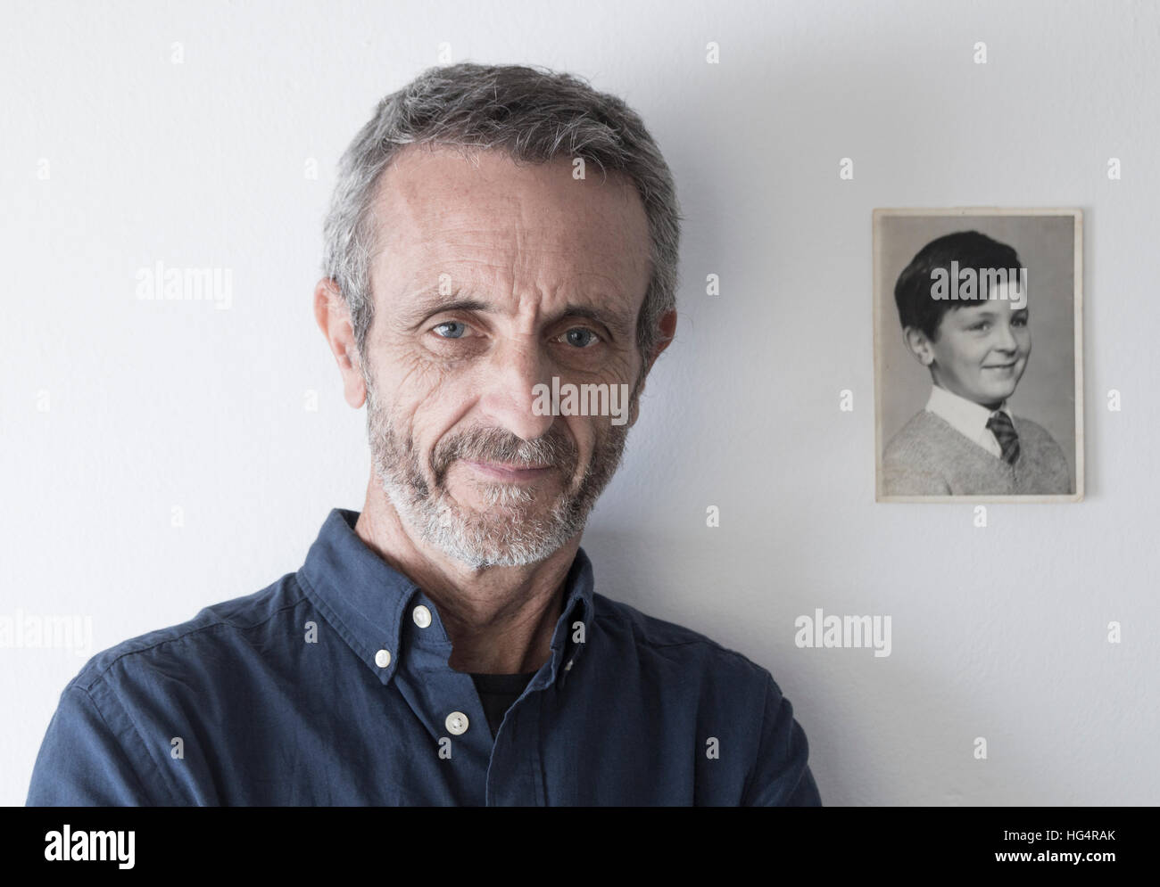 Man in his late fifties with photograph of himself as a young boy. Stock Photo