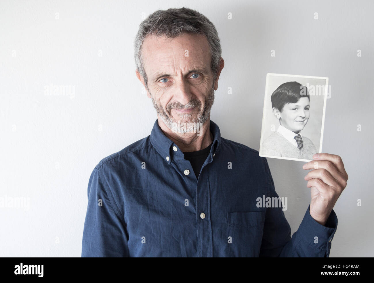 Man in his late fifties with photograph of himself as a young boy. Stock Photo