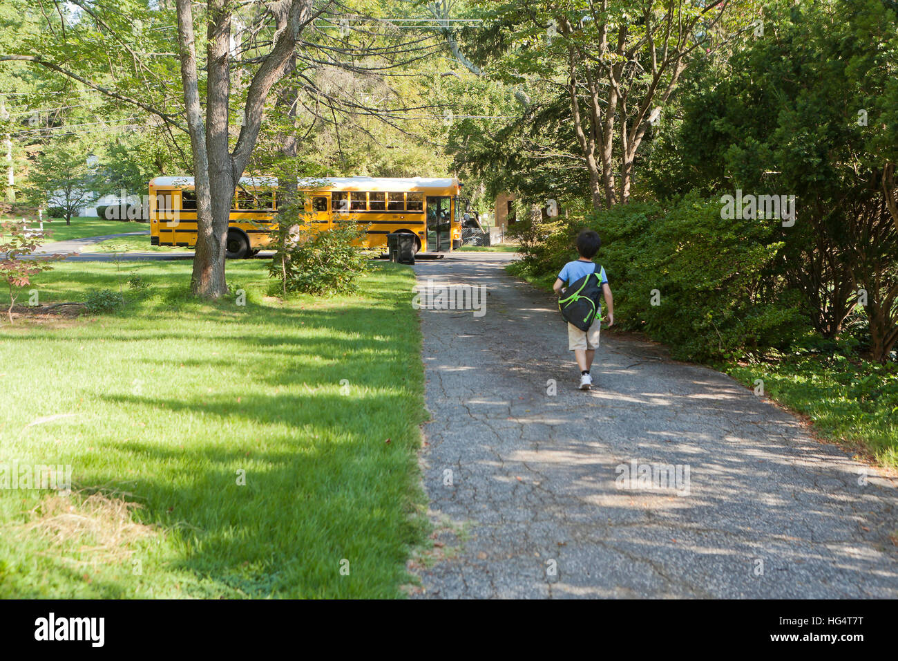 Elementary school student walking toward school bus - USA Stock Photo