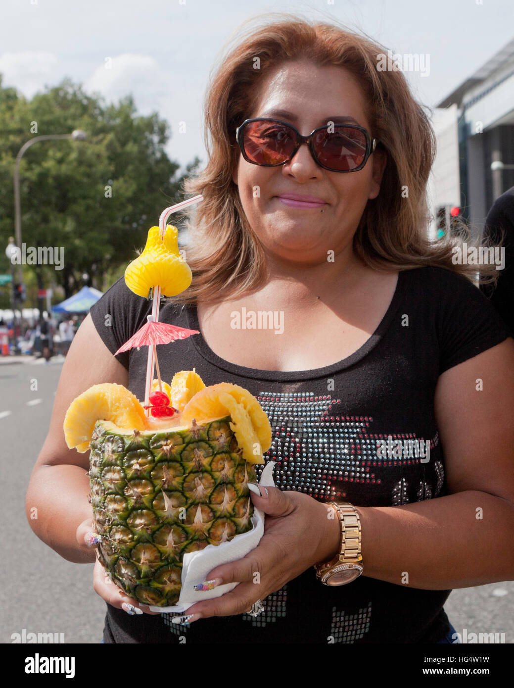 Woman holding a Piña Colada cocktail drink in a decorated pineapple cup - USA Stock Photo